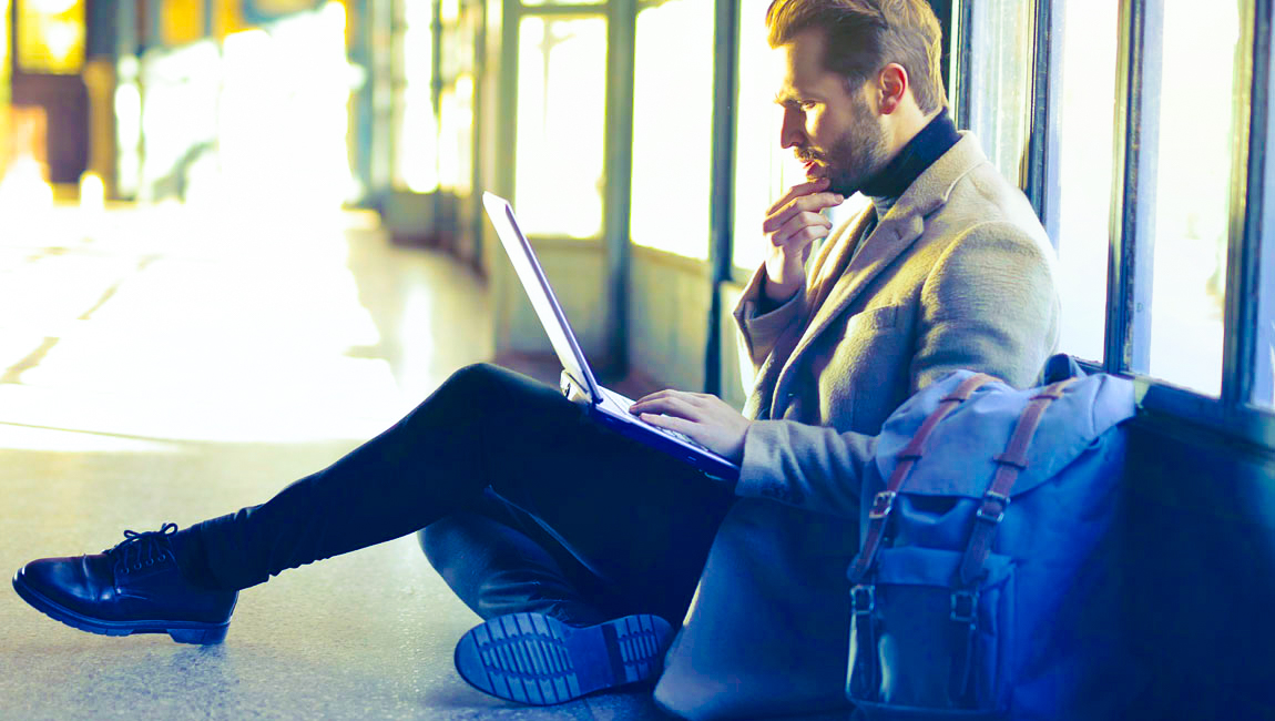 Businessman sitting on floor staring at laptop looking confused